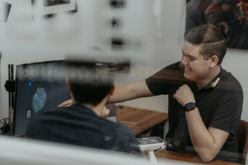 Zwei junge Männer besprechen gemeinsam ein 3D-Modell am Computer im modernen Büro.